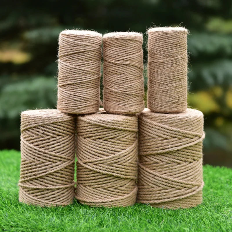 Five cylindrical rolls of natural beige hemp jute rope stacked on green grass