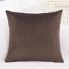 A dark brown velvet decorative cushion cover resting on a white surface.