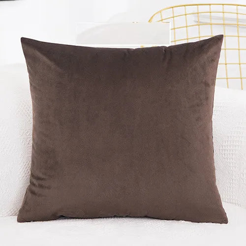 A dark brown velvet decorative cushion cover resting on a white surface.