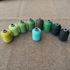 A row of various colored embroidery threads or cords arranged horizontally on a brown fabric surface.