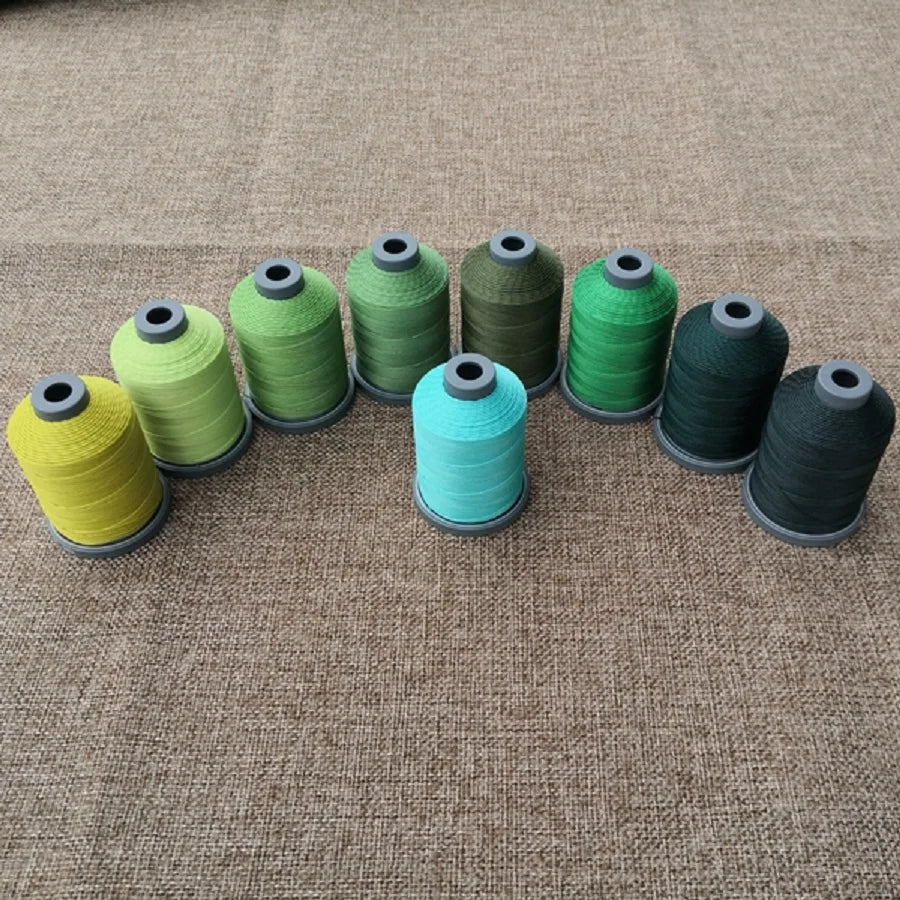 A row of various colored embroidery threads or cords arranged horizontally on a brown fabric surface.