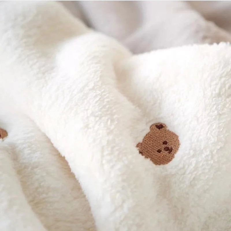Close-up of a white coral fleece flannel blanket with a brown bear appliqué.