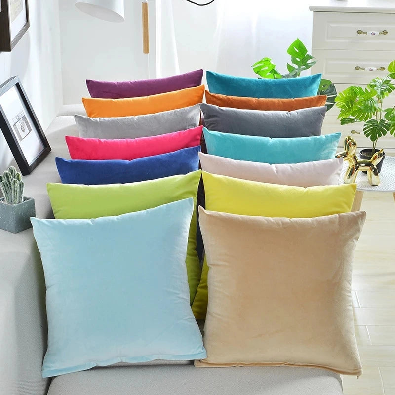 A collection of colorful velvet decorative cushion covers stacked on a sofa.