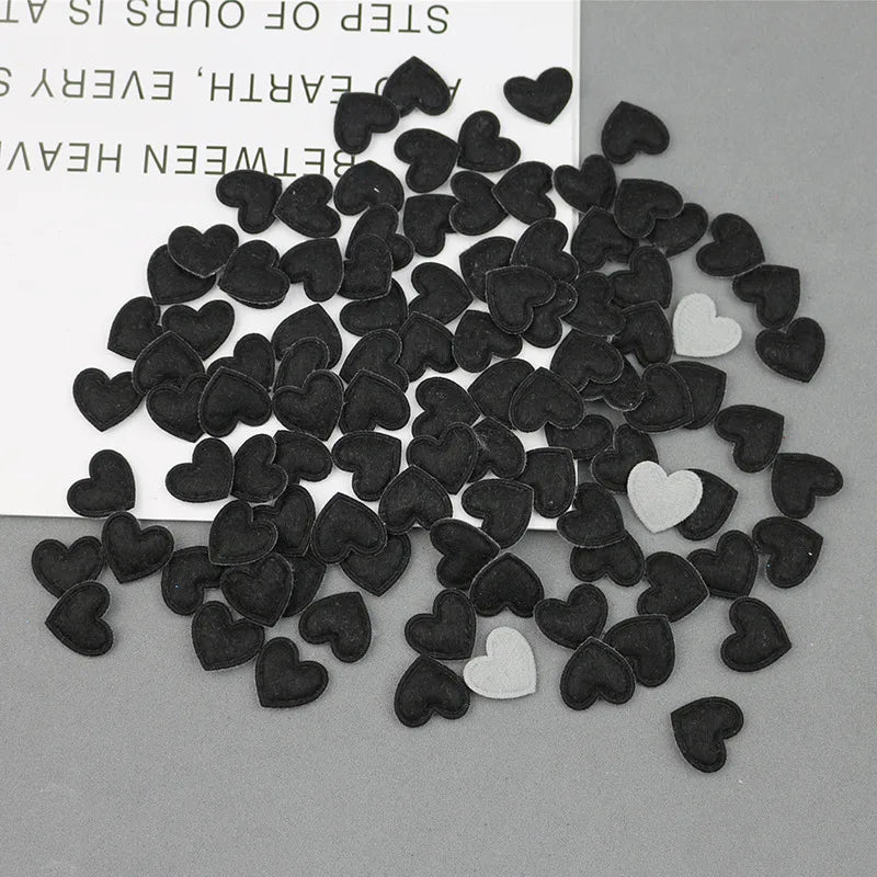 A collection of black and white felt heart appliques scattered on a gray surface.
