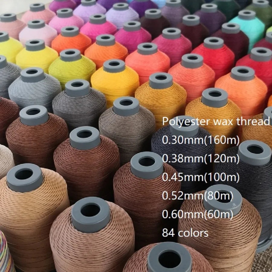 A variety of 84 colors of polyester wax thread embroidery cord spools arranged in a row.