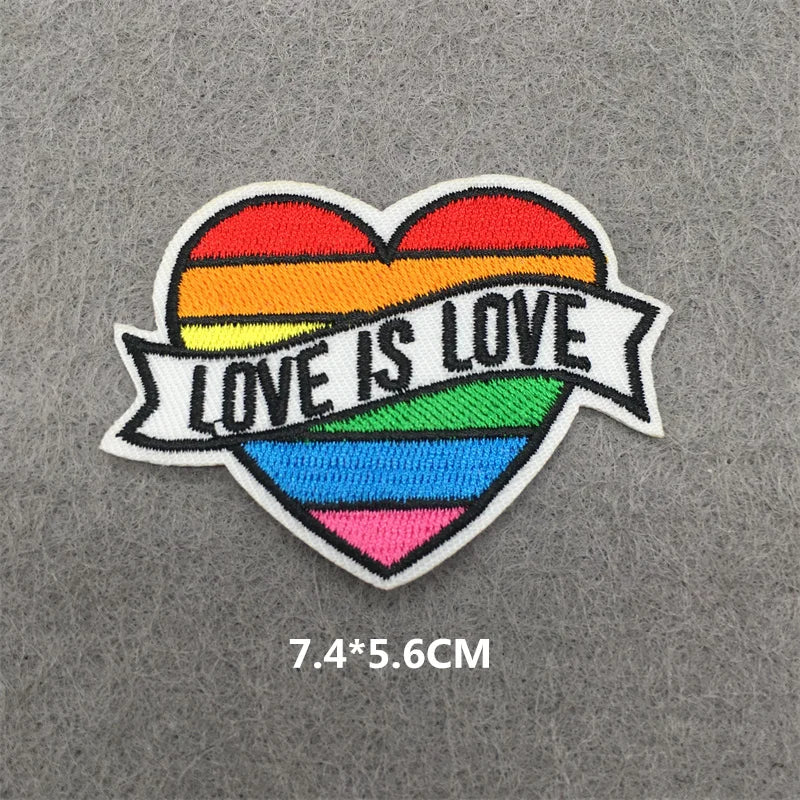 A heart-shaped embroidered patch with a rainbow stripe design and the text Love is Love.