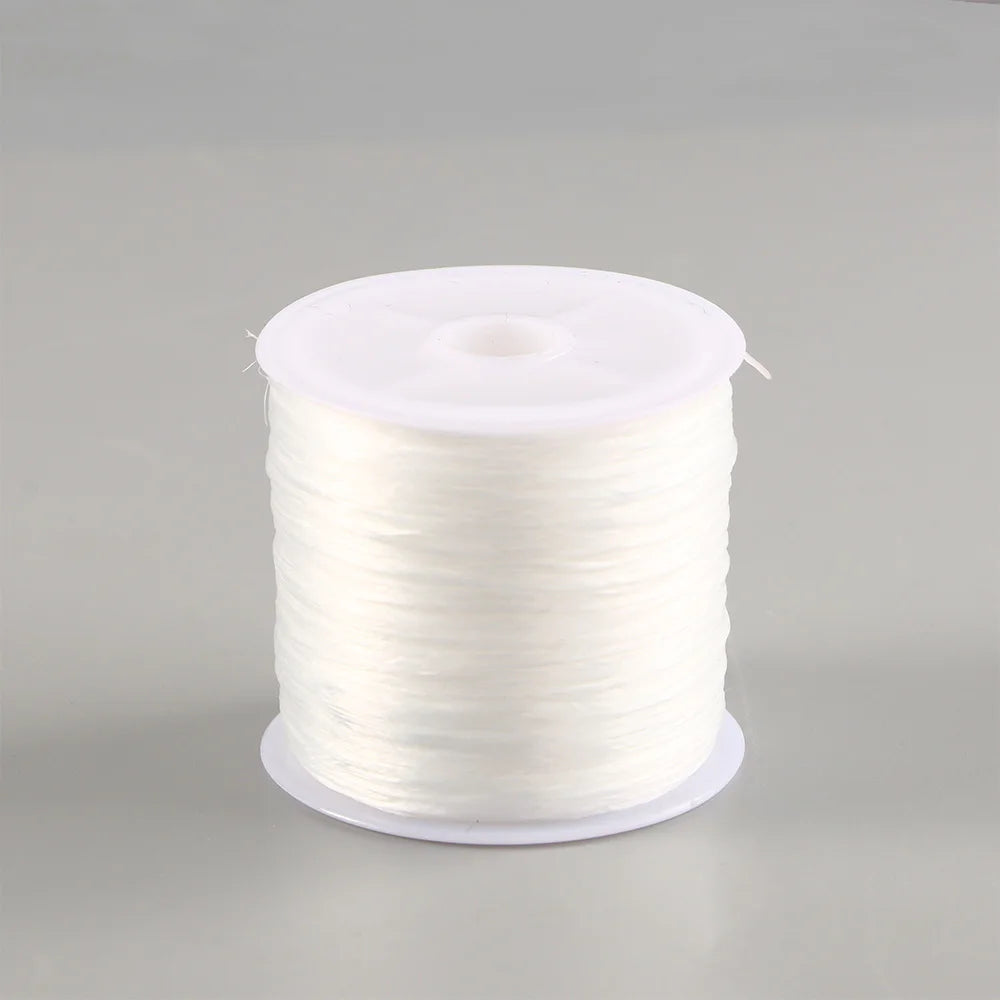 A spool of white flat elastic beading thread for jewelry making.