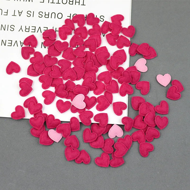 A pile of pink and red felt heart appliques for crafting and decoration.