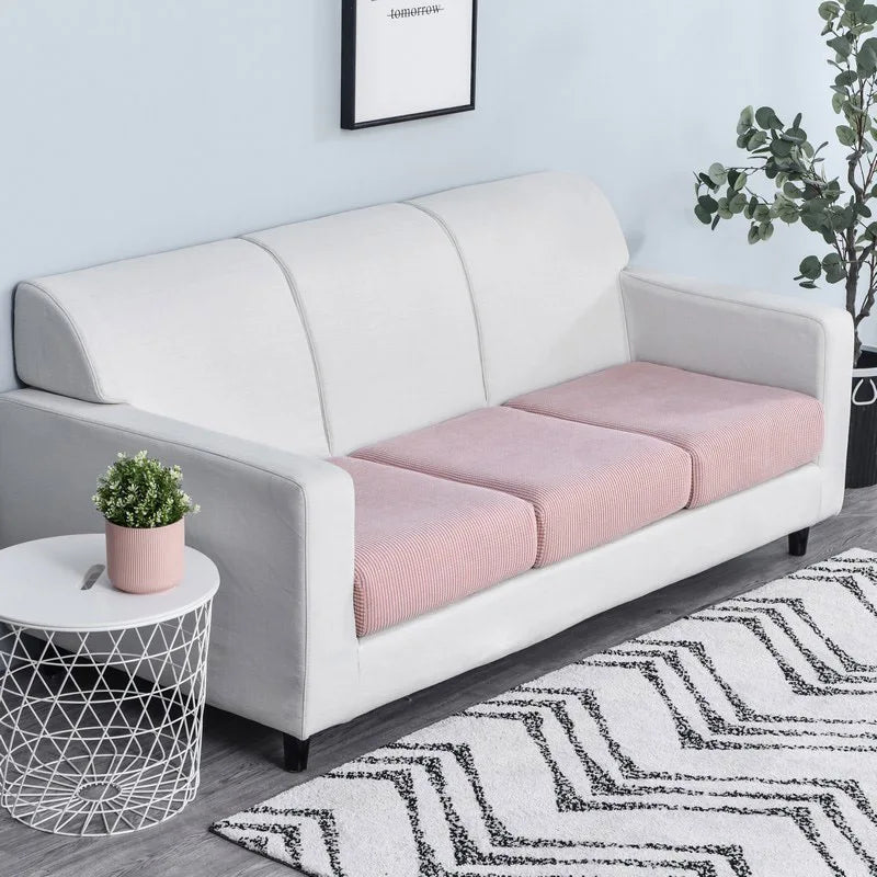 A modern white sofa with a light pink seat cushion cover and a patterned rug.