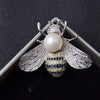 A crystal bee brooch featuring a pearl accent and detailed diamond-like wings.