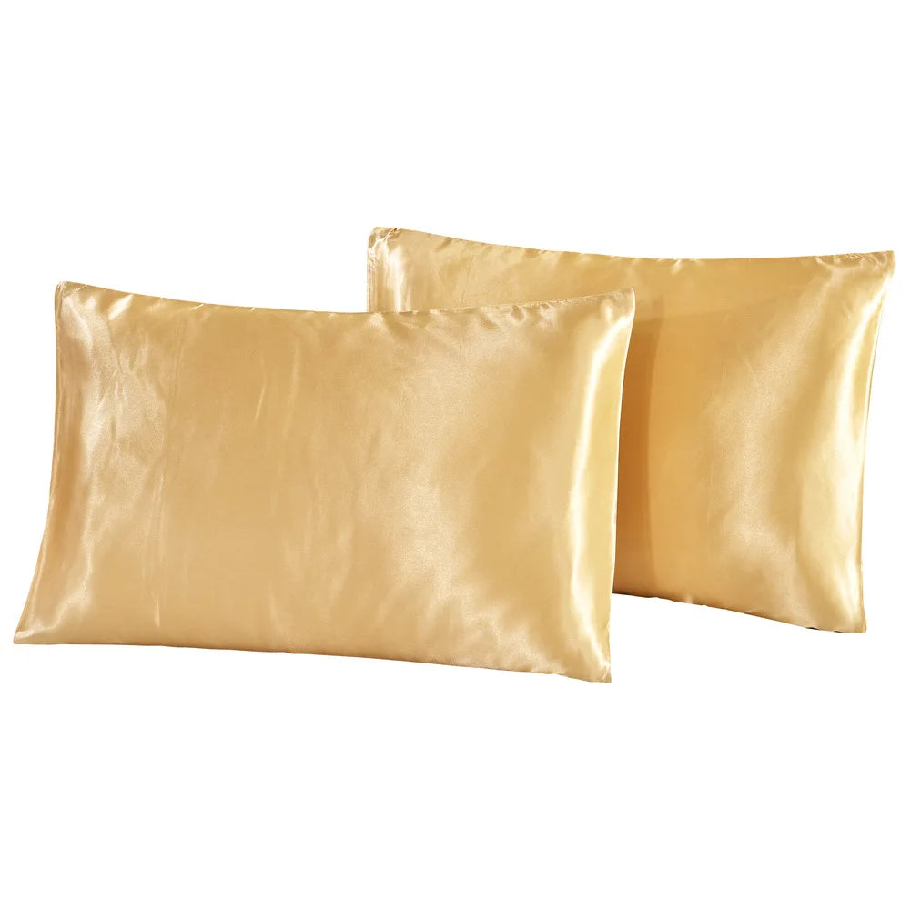 Two smooth golden satin pillowcases folded next to each other.
