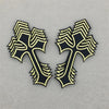 Two black and gold embroidered cross applique patches on a gray background.