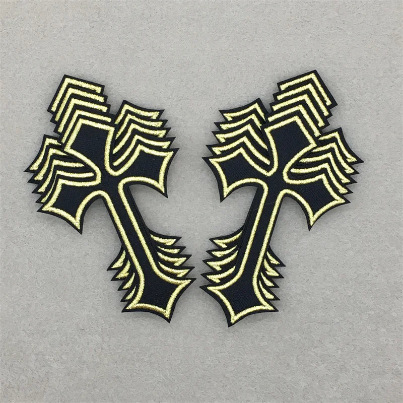 Two black and gold embroidered cross applique patches on a gray background.