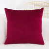 A solid maroon velvet decorative cushion cover resting on a white surface.