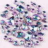 A collection of silver claw rhinestones and decorative gems scattered on a white background.