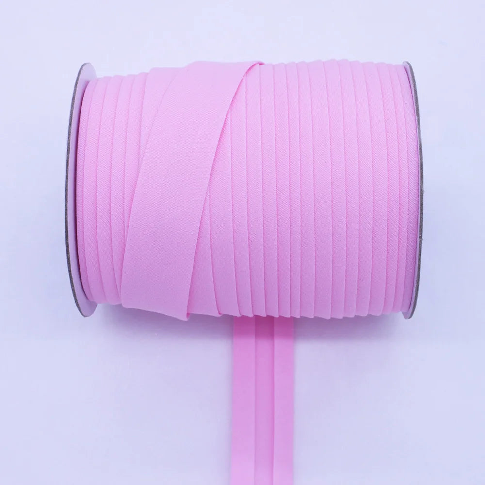 Pink durable bias tape binding ribbon rolled on a spool with a pink stick.