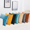 A collection of solid velvet decorative cushion covers in shades of teal, yellow, olive green, gray, and burnt orange.