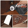 A hand holds a leather cutting tool and a ruler on a dark surface, next to leather material.