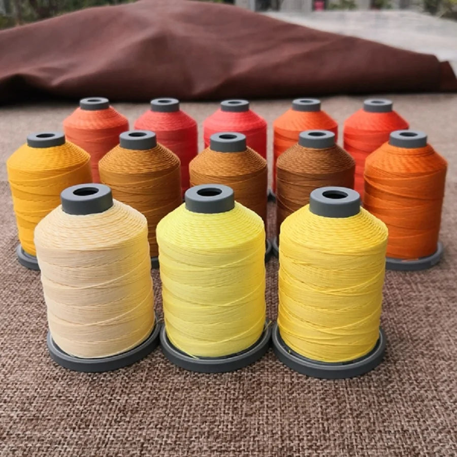 A collection of brightly colored wax thread embroidery cords in various shades of orange, yellow, and red are displayed on a 