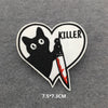 A black cat silhouette with claws and a knife is embroidered inside a heart-shaped patch with the word KILLER above it.