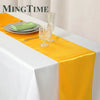 Elegant satin gold table runner with glassware and a napkin set on a white tablecloth