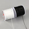 A spool of black flat elastic beading thread next to a spool of white flat elastic beading thread.