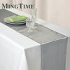 Elegant satin gray table runner set with green napkin and glassware on a white tablecloth