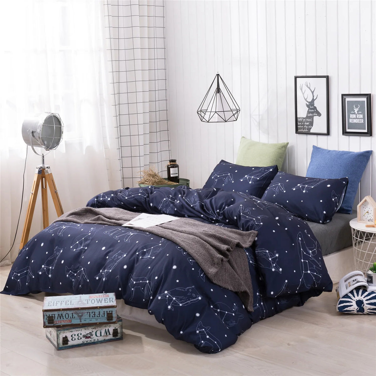 A dark blue duvet cover set featuring a starry sky pattern displayed on a bed in a bright room.