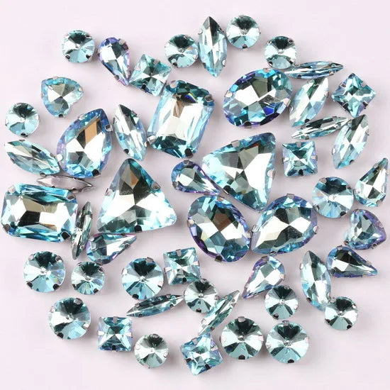 A scattered collection of sparkling blue and clear silver claw rhinestones.