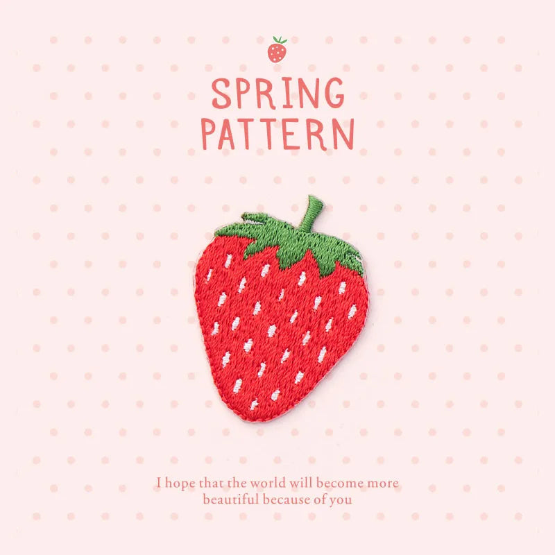 A pink background features a hand-stitched red strawberry embroidery patch with green leaves and the text Spring Pattern.
