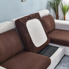 A brown stretch sofa seat cushion protector slipcover is shown on a white sofa.