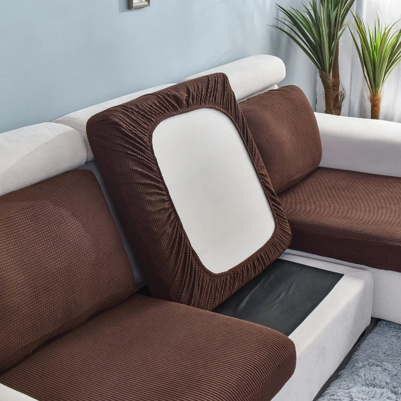 A brown stretch sofa seat cushion protector slipcover is shown on a white sofa.