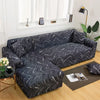 A dark gray and white patterned L-shaped sofa protector cover placed on a wooden floor.