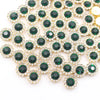A close-up of green and clear crystal rhinestone sew-on buttons arranged in a sunflower pattern.