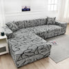 A gray L-shaped sofa protector cover displayed on a light gray rug in a bright room.
