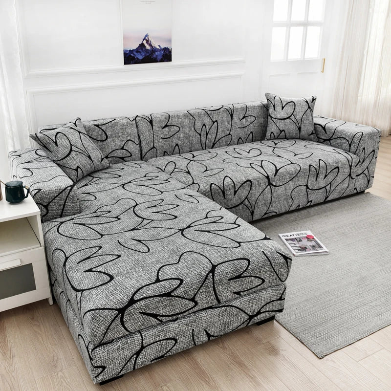 A gray L-shaped sofa protector cover displayed on a light gray rug in a bright room.