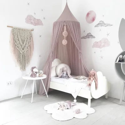 A pink princess canopy mosquito net for kids with sheer fabric draping and decorative clouds on a white wall.