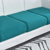 A white sofa seat cushion protector slipcover with teal fabric cushions on a gray floor.