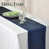 Elegant navy satin table runner with a green napkin, glassware, and silverware on a white tablecloth.