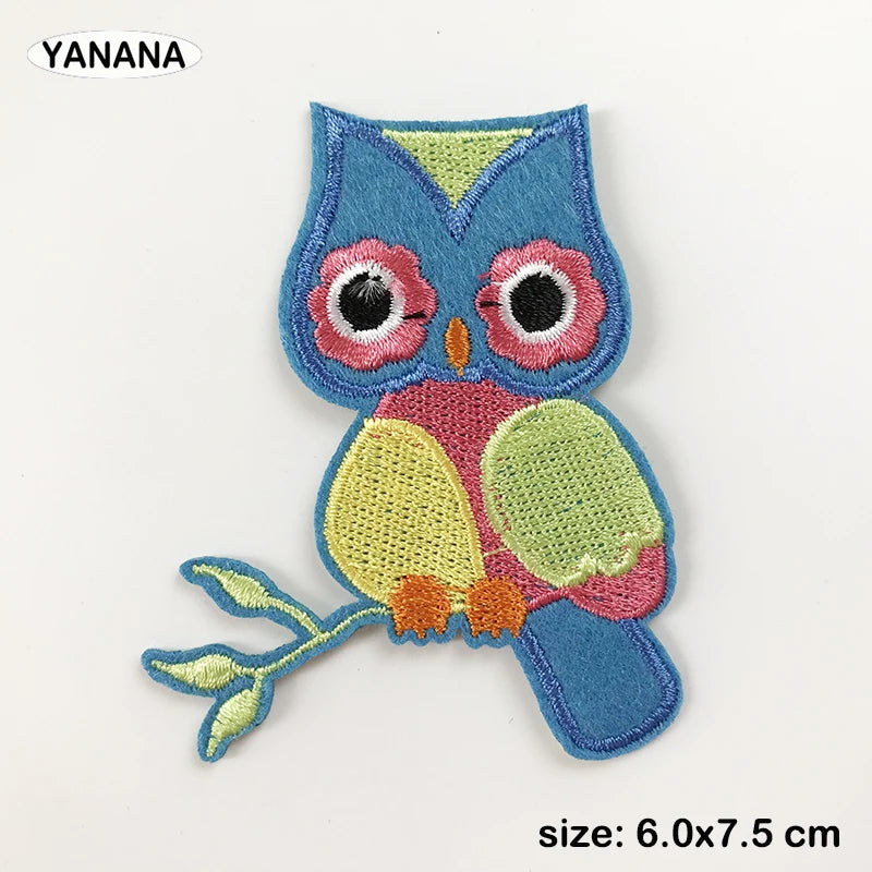 A blue and pink embroidered owl patch with yellow accents.