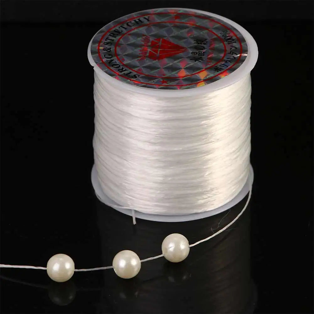 Spool of white stretchy beading thread with a decorative label and a strand unwound below.