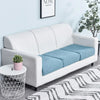 A white sofa with light blue seat cushions and a patterned rug in a bright room.