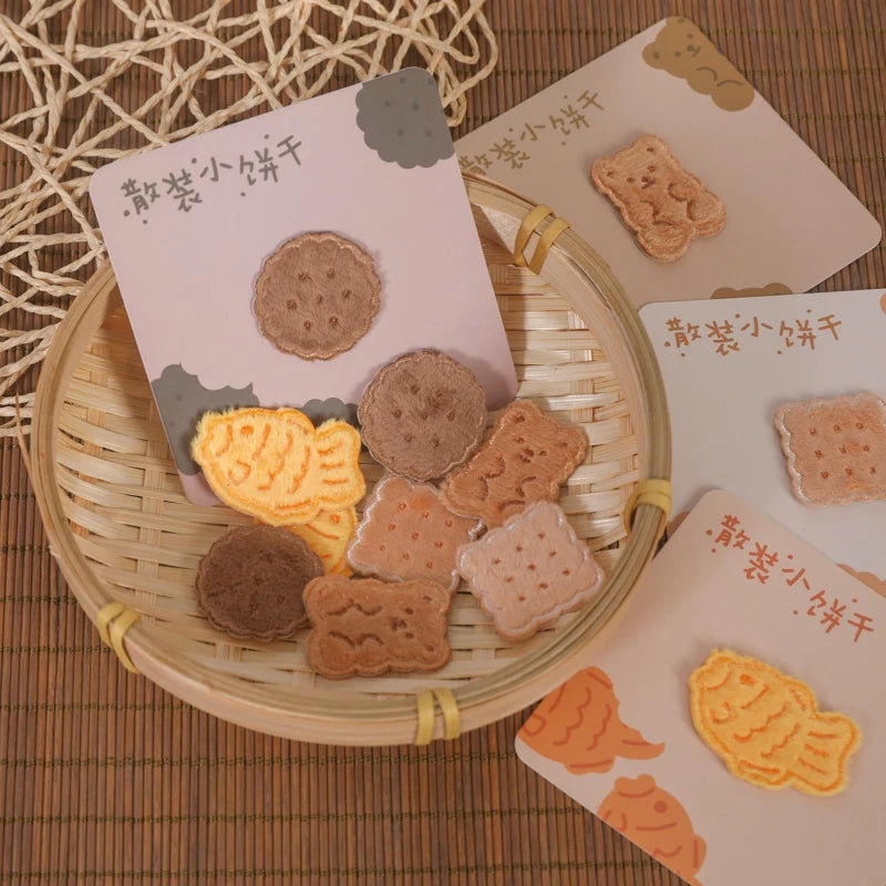 A collection of iron-on embroidered food and drink patches in various shapes and colors arranged on a bamboo tray.