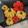 A collection of orange and red polka-dotted pumpkin plush cushions displayed on a black leather sofa.