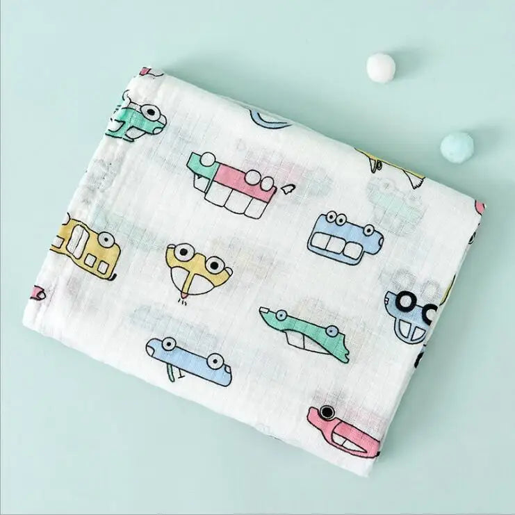 A white muslin swaddle blanket featuring a repeating pattern of cute, stylized animal designs in pastel colors.