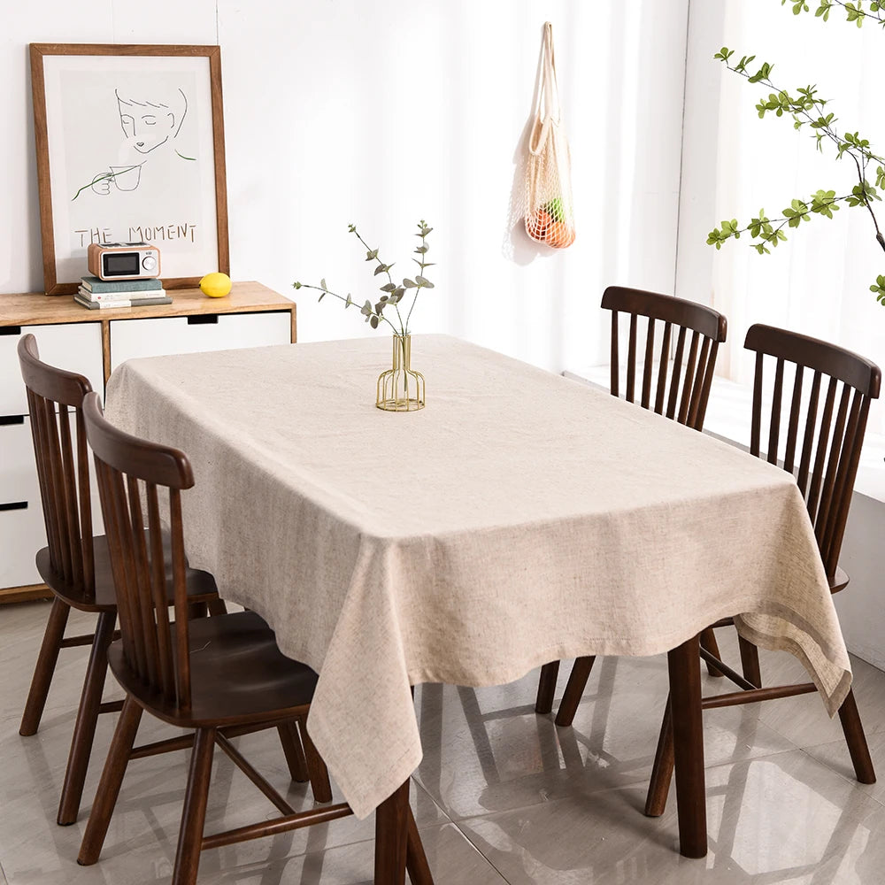 A long table set for dining featuring beige linen tablecloths and matching napkins.
