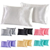 A collection of silky satin pillowcases in various colors including white, gray, black, pink, and teal.