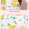 A white muslin swaddle blanket with yellow and green designs is shown next to a digital watch.