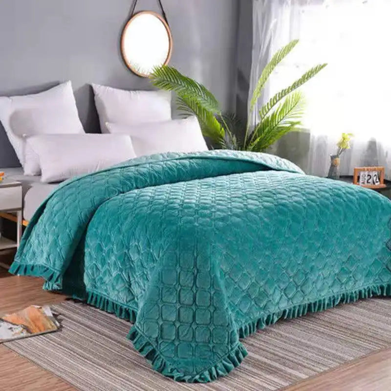 Teal crystal velvet quilted bedspread draped over a bed in a bright room.