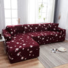 A deep burgundy printed sofa protector cover displayed on a modern living room floor.